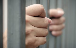 hands holding prison bars