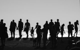 Monochrome image of silhouettes of people walking on the hill by the sea